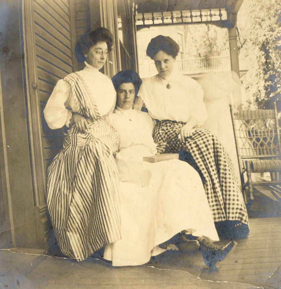 Black and white photograph of three women sitting on a porch.